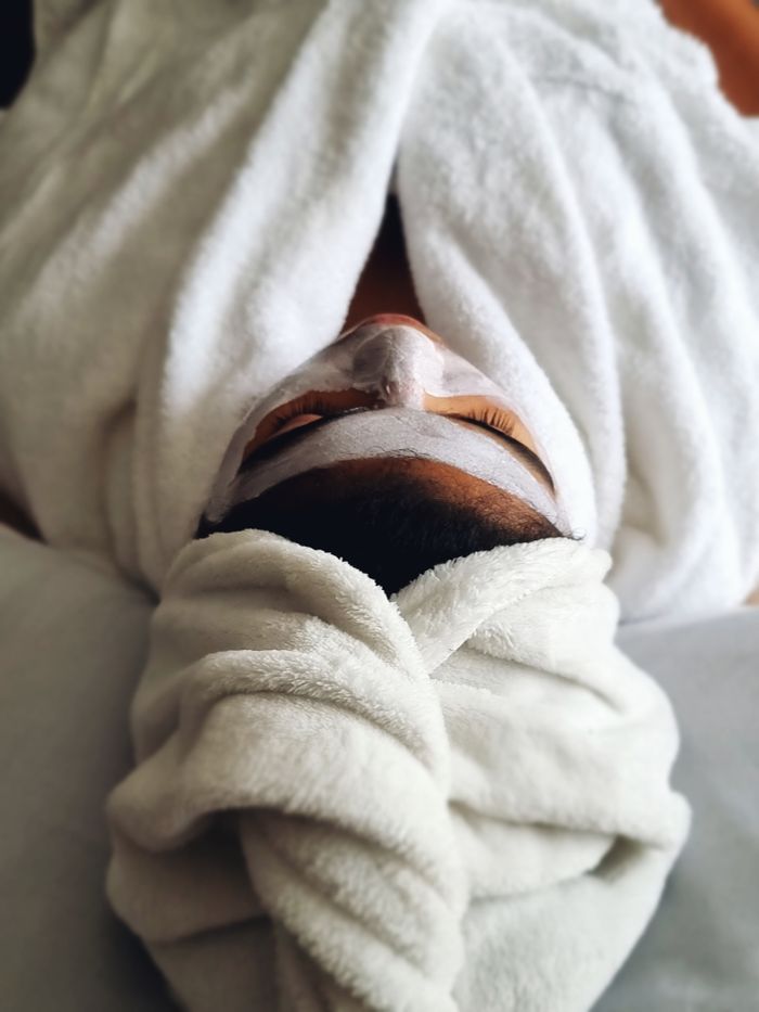 A woman enjoying a relaxing spa treatment with a face mask and towel wrap.
